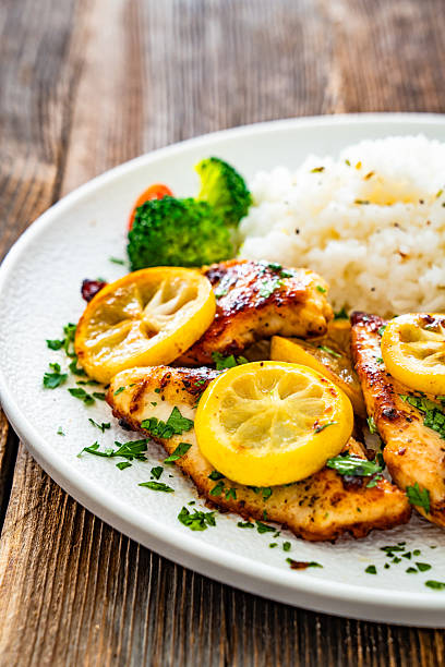 istock Lemon chicken escalopes with rice on wooden table 2223055725