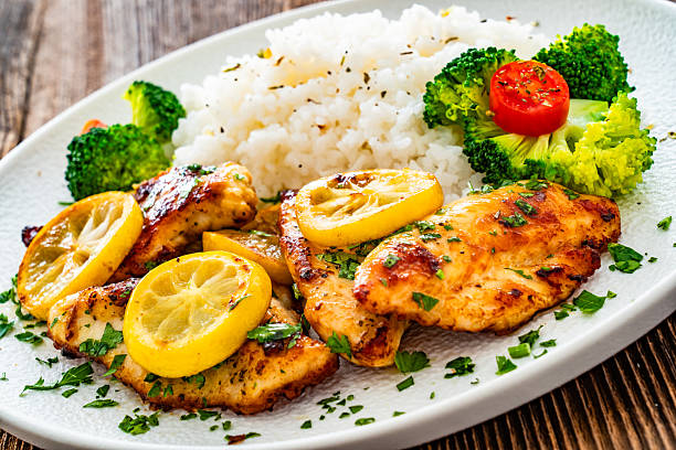 istock Lemon chicken escalopes with rice on wooden table 2223055883