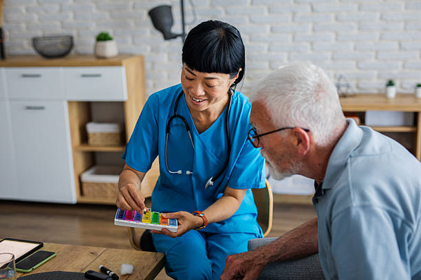 istock Friendly Healthcare Professional Helping Senior with Pill Organizer 2223057931