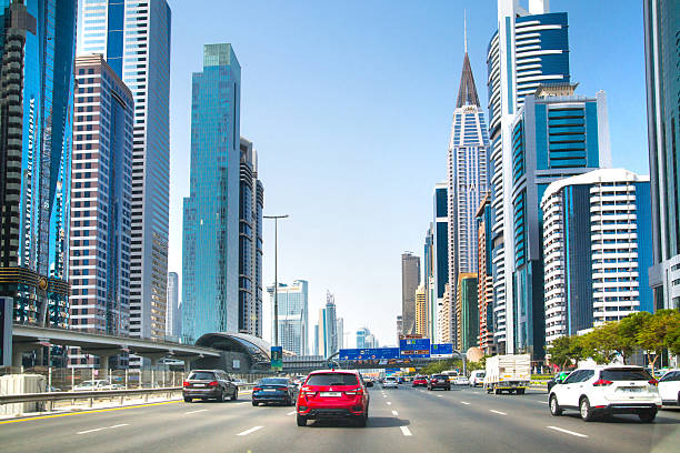 UAE, Abu Dhabi - August 20, 2024: Driving car via the Sheikh Zayed road with iconic skyscrapers and metro station