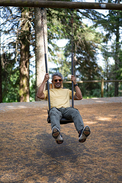 istock Man playing on a swing in a park 2223064619