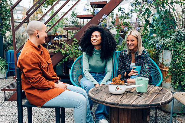 Two female friends talking at backyard before garden party on summer day