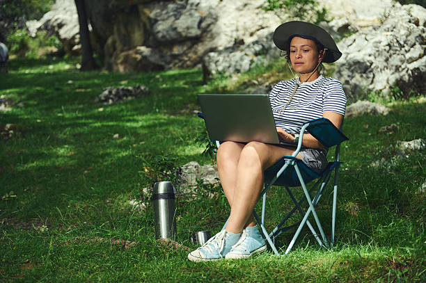 istock Woman Working Remotely While Relaxing in Nature, Sitting Outdoors With a Laptop 2223069891