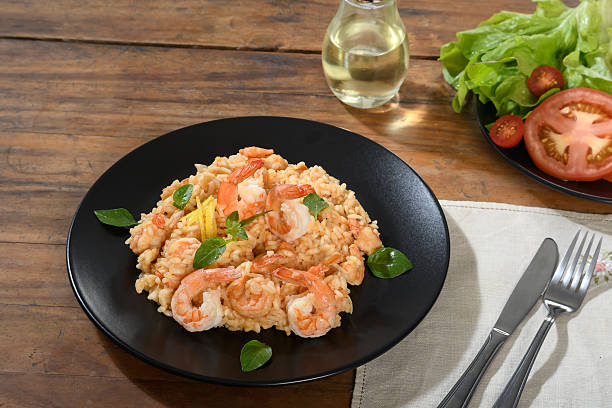 istock Shrimp risotto with lemon and basil on a black plate on a wooden table 2223072490