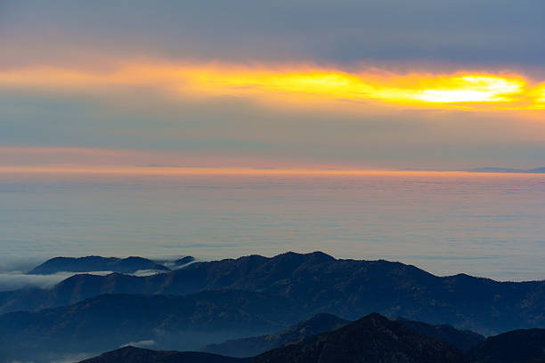 Stunning sunset view over the blue mountains of Sequoia National Park, California, showcasing layered peaks beneath a colorful sky with soft clouds.