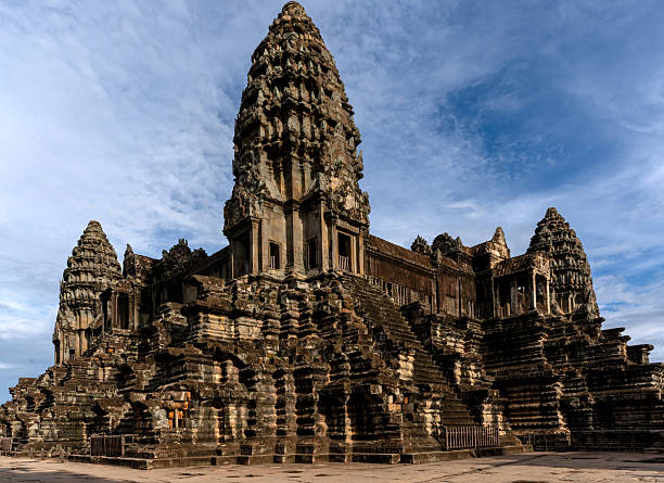 A view of the central tower of Angkor Wat captured under a dramatic sky. The intricate carvings and weathered stone steps showcase the grandeur of Khmer architecture at this iconic UNESCO World Heritage Site.
