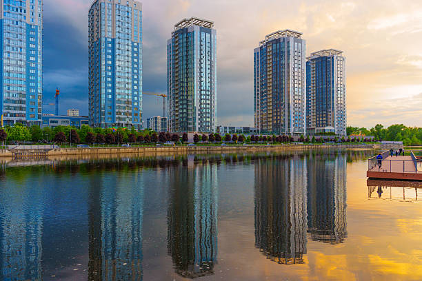Kyiv, Ukraine - May 19, 2025: Wide-angle view of the RiverStone residential complex in Kyiv, showcasing reflective high-rise buildings and a serene river at sunset.