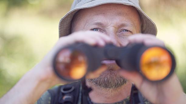 istock Man in the summer forest. Bird watching adventure. Looking through binoculars. Birding 2223074555