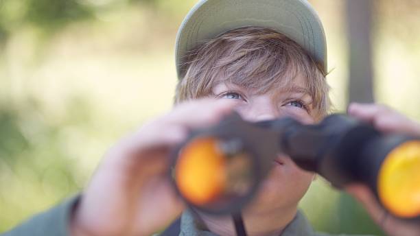 istock Boy backpacking in the green summer forest. Bird watching adventure. Looking through binoculars Birding 2223074557