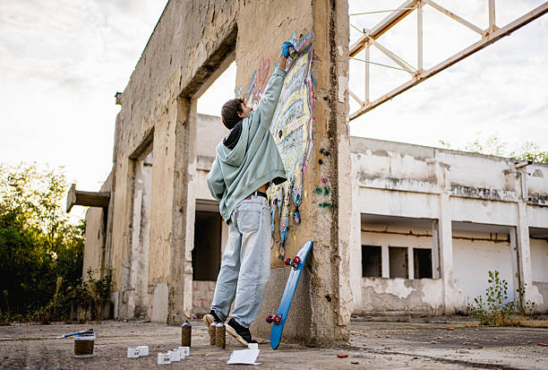 istock Young artist spray painting graffiti on abandoned building wall 2223076565