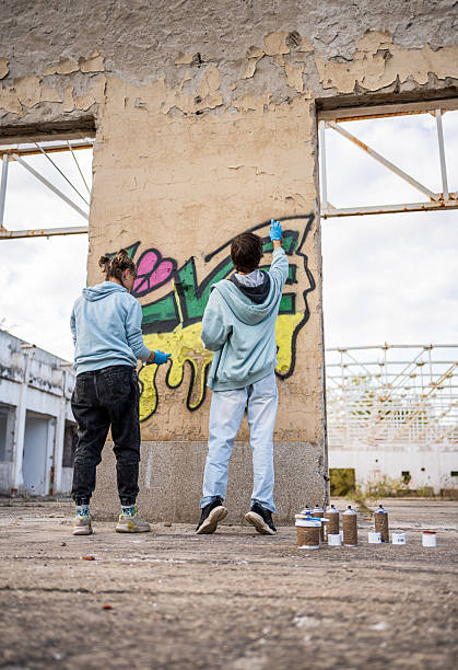 istock Two young graffiti artists painting on a derelict building wall 2223077144