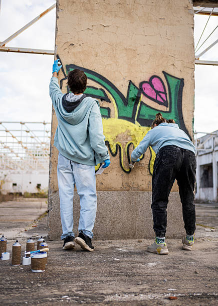 istock Two young graffiti artists painting on a wall in an abandoned building 2223077166