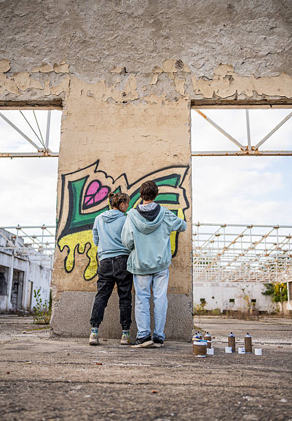 Top view of street artist painting graffiti on generic wall - Modern art concept with urban guy performing and preparing live murales with green aerosol color spray - Bright vivid filter