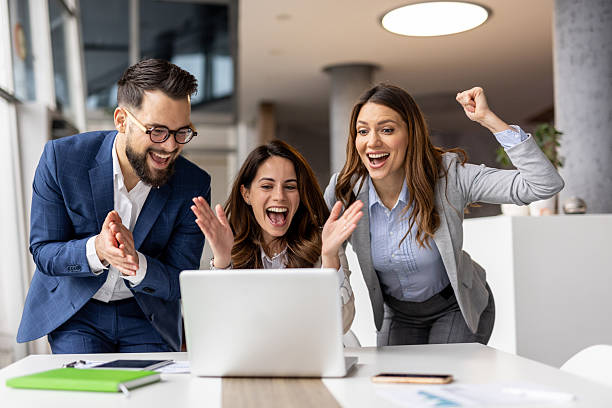 istock Excited business team celebrating success while looking at laptop in the office 2223077366