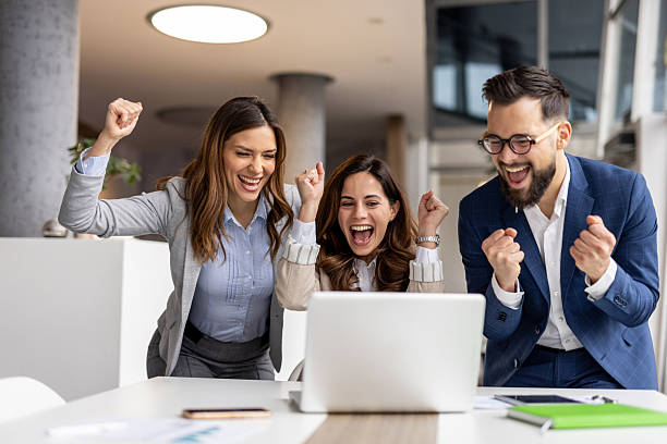istock Excited business team celebrating success while looking at laptop in office 2223077578