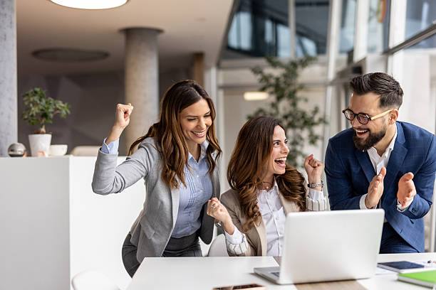 istock Excited business team celebrating success while looking at laptop 2223077581