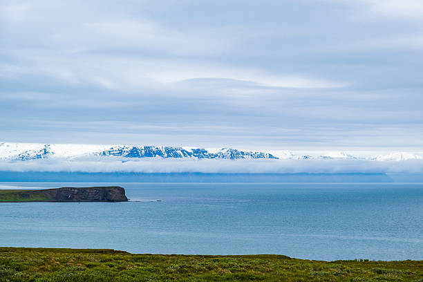 Atlantic ocean shore on north Iceland, snow covered mountains in mist