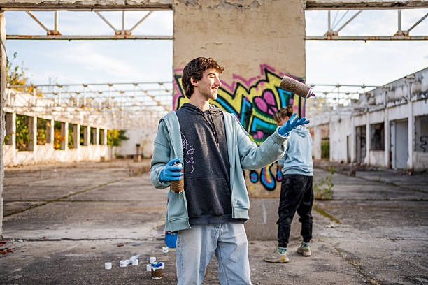 istock Young graffiti artists playing with spray cans in abandoned building 2223077899