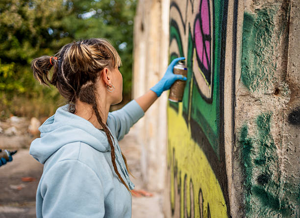 istock Young artist spray painting a graffiti on a wall 2223078000