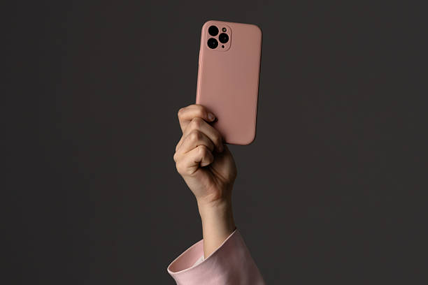 istock Hand Holding Modern Smartphone with Pink Case against Dark Background 2223078055