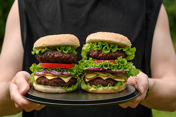 istock man holding a sandwich, big hamburger, serving fast food 2223079467