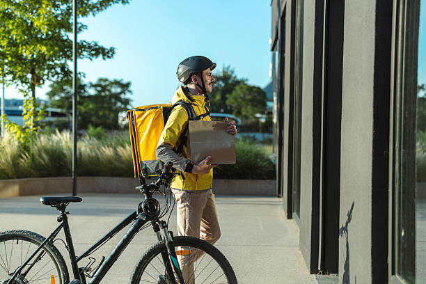 istock Delivery worker carrying a package on foot near a parked bicycle 2223082765