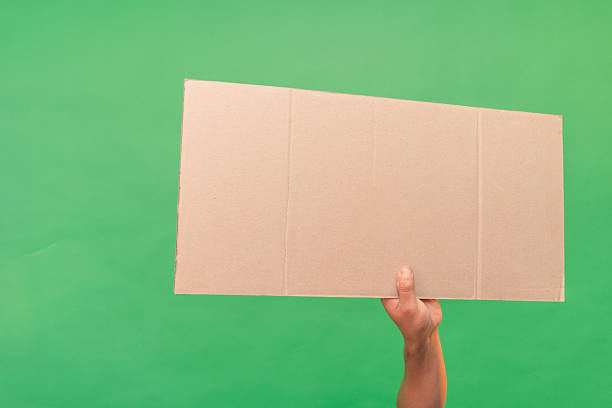 istock Hand holding blank cardboard sign on green screen background 2223082869