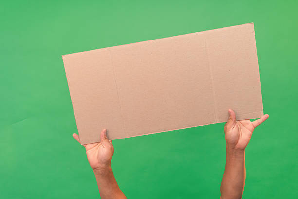 istock Hands holding blank cardboard sign on green screen background 2223083494