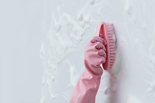 Woman hand cleaning blue wall with brush.