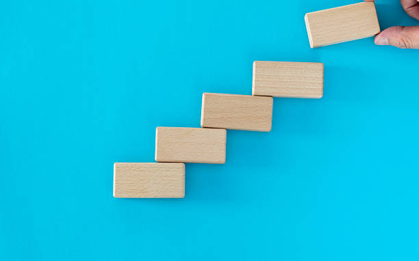 istock Human hand building stairs with blocks 2223084545