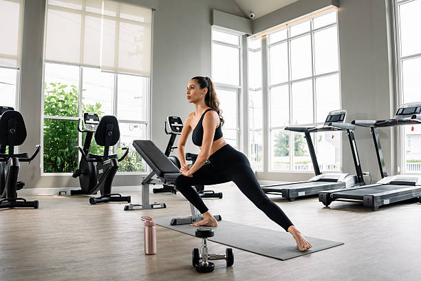 a woman is doing a yoga pose in a gym. she is wearing a black tank top and black pants - tập gym hình ảnh sẵn có, bức ảnh & hình ảnh trả phí bản quyền một lần