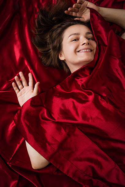 istock Happy woman sleeping on red bed linen 2223085084