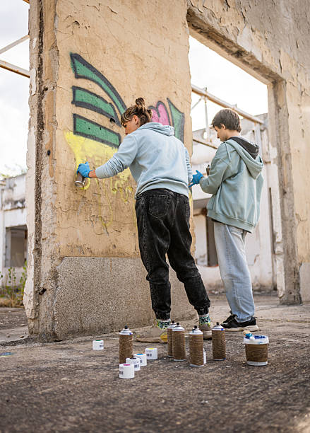 istock Two young artists painting graffiti on a derelict building wall 2223085262