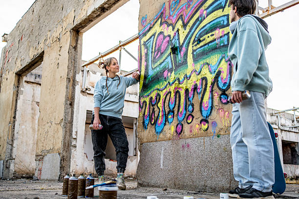 istock Two young graffiti artists creating street art on abandoned building wall 2223085307
