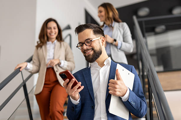 istock Businessman using smartphone on stairs in office with colleagues 2223085309