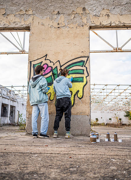 istock Two young artists painting graffiti on a derelict building wall 2223085441