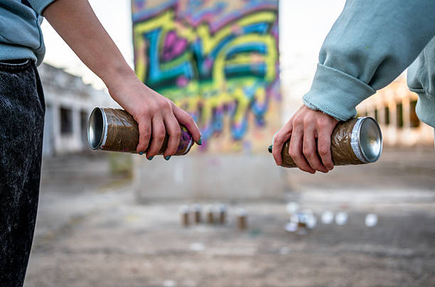 Two young graffiti artists are getting ready to create street art in an abandoned urban area, holding spray paint cans