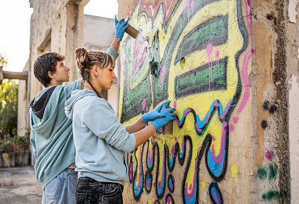 istock Two young graffiti artists painting a wall in an abandoned building 2223085740