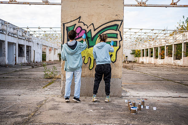 istock Two young artists painting graffiti on a wall in abandoned building 2223085908