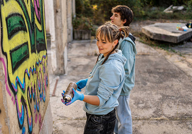istock Two young graffiti artists painting a wall with spray cans 2223085947