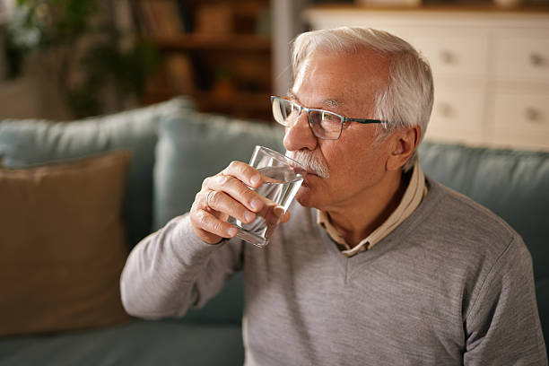 istock Senior man drinking water on the sofa at home 2223086624