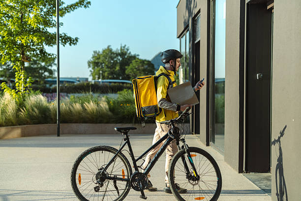 istock Delivery worker carrying a package on foot near a parked bicycle 2223088152