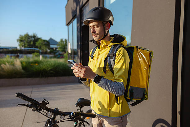istock Courier on bike using smartphone outside building during daytime work routine 2223088259