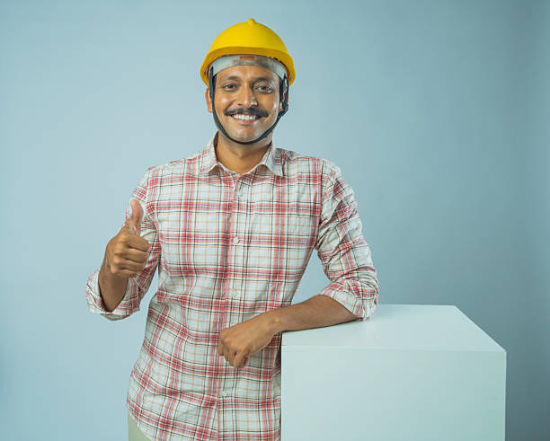 Engineer showing OK gesture against white background Portrait of smiling male architect wearing hardhat showing thumbs up and standing by block against white background top architects stock pictures, royalty-free photos & images