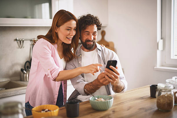 istock Happy couple using smartphone and having breakfast in kitchen at home 2223090959
