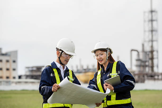 istock Two Engineers Happily Discussing a Project Plan with a Blueprint and Tablet. Two people wearing safety gear and looking at a drawing 2223093290