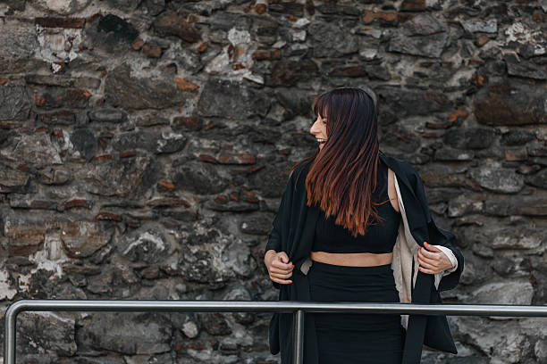 istock Smiling young female in black outfit by stone wall 2223096794