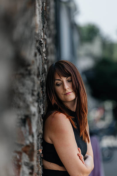 istock Young caucasian female leaning against wall outdoors, pensive expression 2223096852
