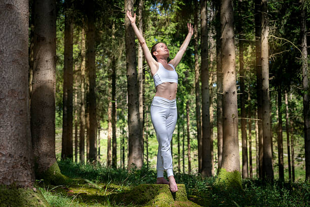 istock Woman practicing relaxation and mindfulness outdoors in a forest  with arms raised. 2223099378