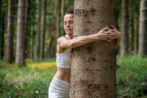 istock Sporty woman hugging tree in forest embracing nature 2223099408